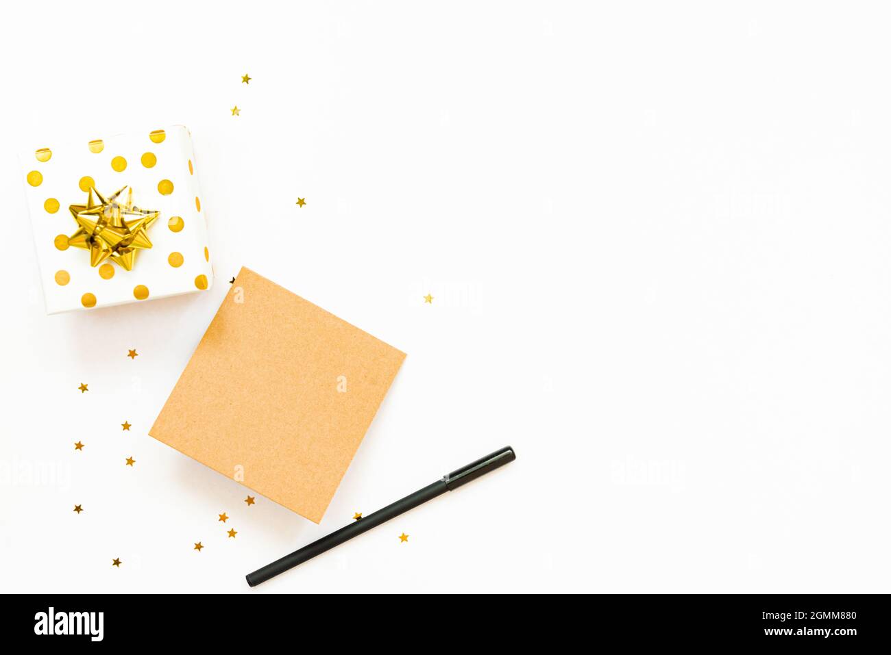 Vue de dessus des boîtes-cadeaux en pointillés dorés et de la carte vide sur fond blanc. Espace de copie, maquette. Banque D'Images