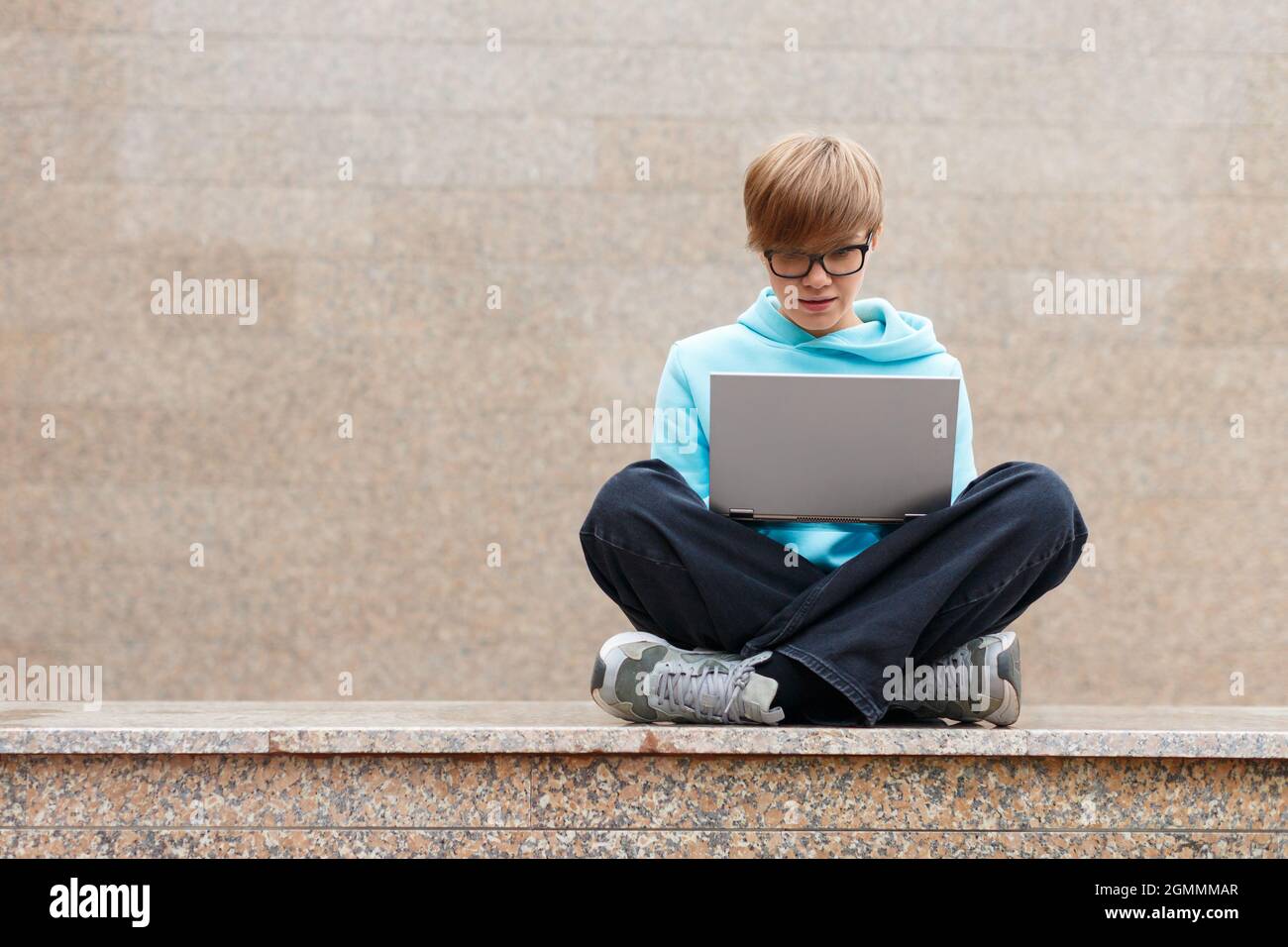 Concept moderne de technologie sans fil - femme aux cheveux courts avec un ordinateur portable dans un environnement urbain. Elle travaille intenly, assis sur le parapet contre t Banque D'Images