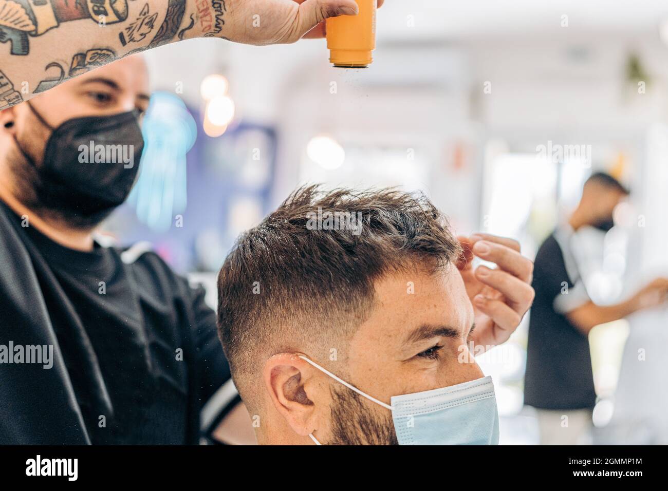 Coiffeur jetant de la poudre de talc sur les cheveux d'un homme portant un  masque dans un salon Photo Stock - Alamy