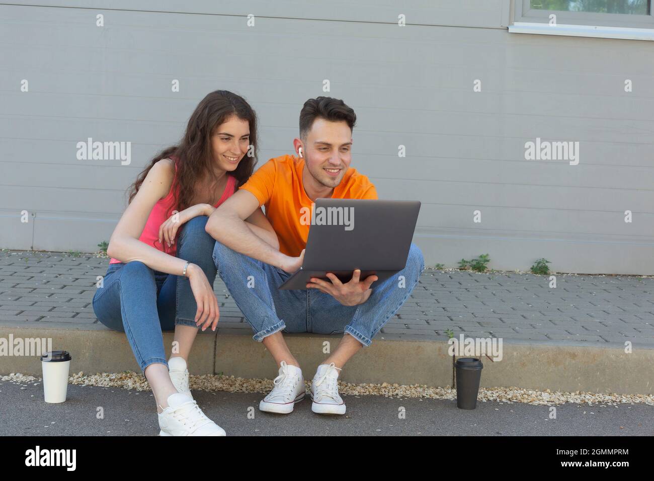 Jeune couple utilisant un ordinateur portable sur le trottoir Banque D'Images