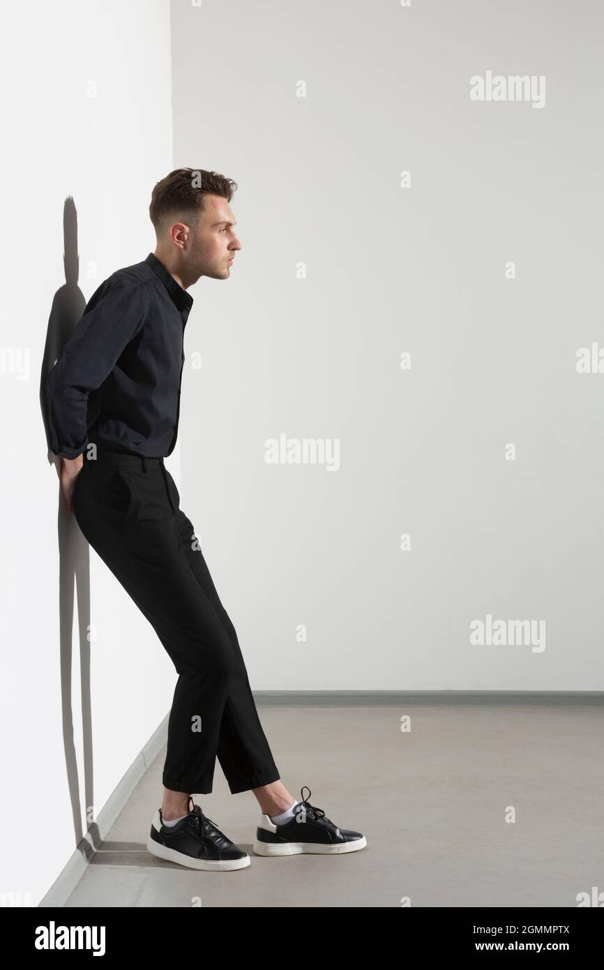 Young man leaning against wall Banque D'Images