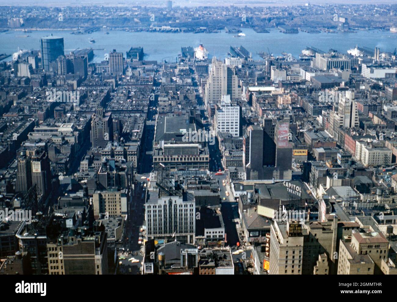 New York City, États-Unis – vue vers l’ouest sur la ville, en direction de l’Hudson River et des quais de la ville c. 1954. La rue qui traverse de gauche à droite en premier plan est Broadway avec un signe pour le théâtre Capitol (notez l'orthographe britannique du signe) haut au-dessus du niveau de la rue. Un paquebot est amarré au port sur l'une des jetées. Cette image provient d'une ancienne transparence couleur Kodak prise par un photographe amateur, une photographie vintage des années 1950. Banque D'Images