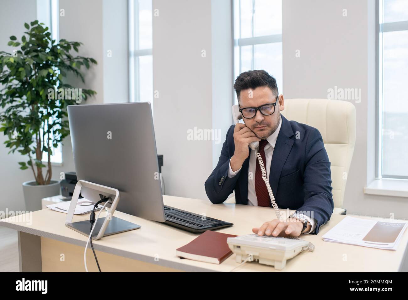 Homme d'affaires ou directeur d'entreprise en composant le numéro de téléphone de son lieu de travail au bureau Banque D'Images