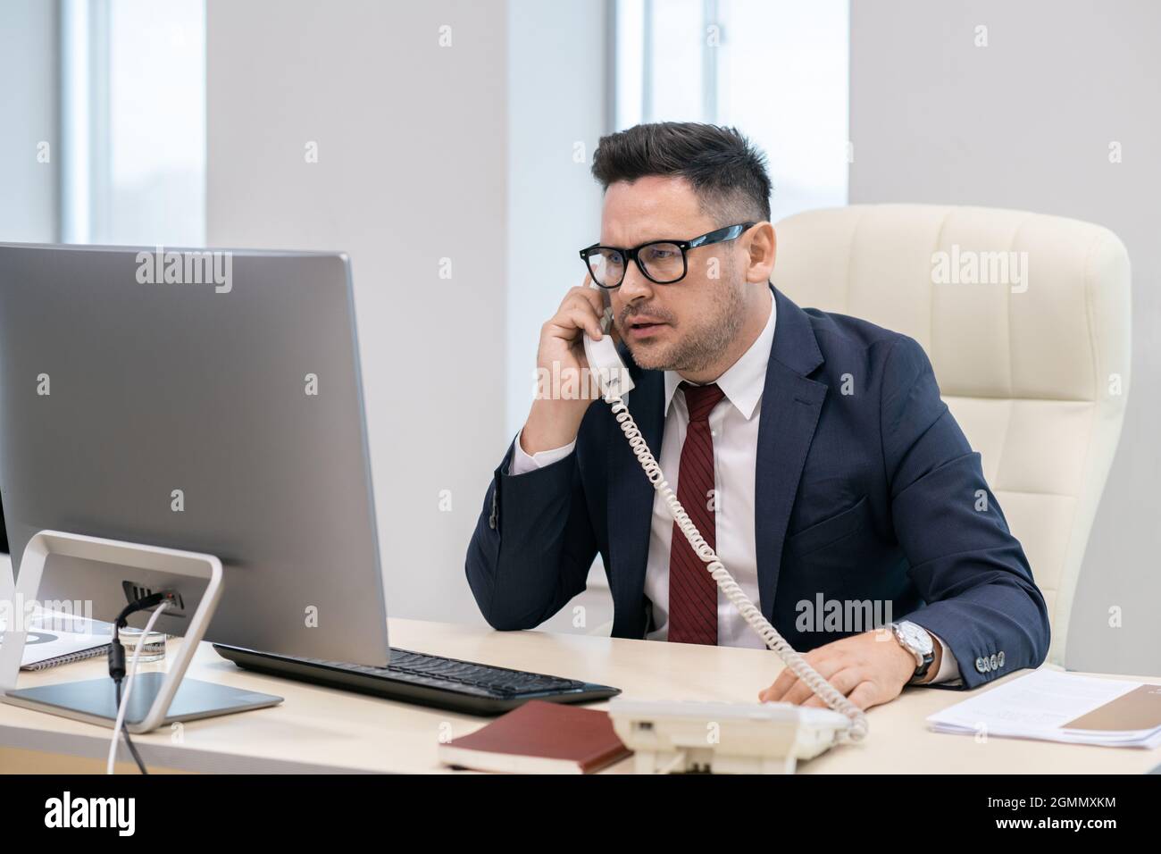 Directeur de l'entreprise contemporaine parlant au téléphone par le lieu de travail au bureau Banque D'Images