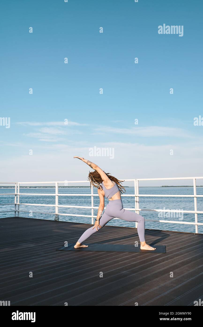 Jeune femme active pieds nus faisant un exercice de yoga d'étirement le matin d'été Banque D'Images