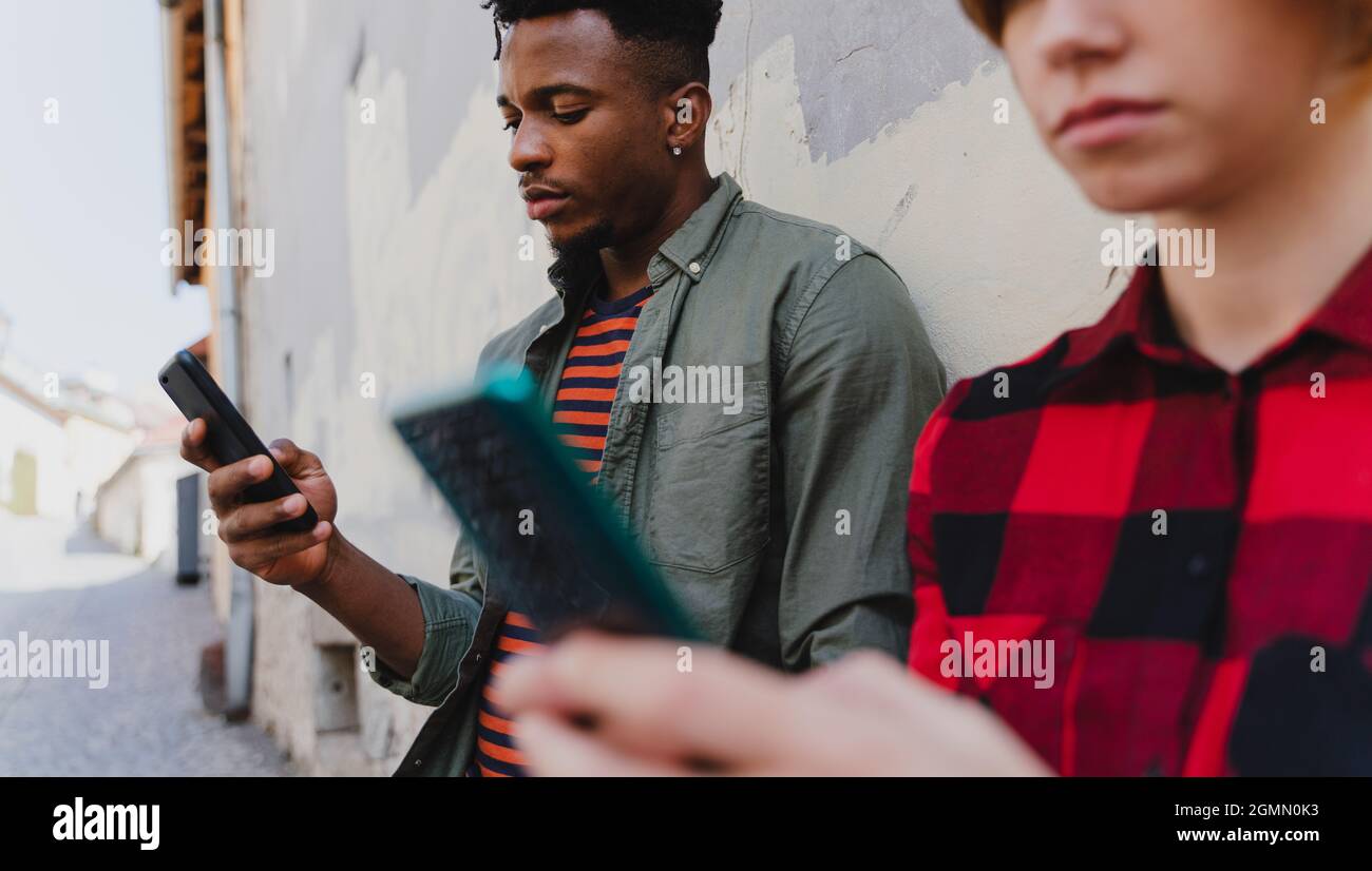 Jeune couple mixte utilisant un smartphone à l'extérieur de la ville. Banque D'Images