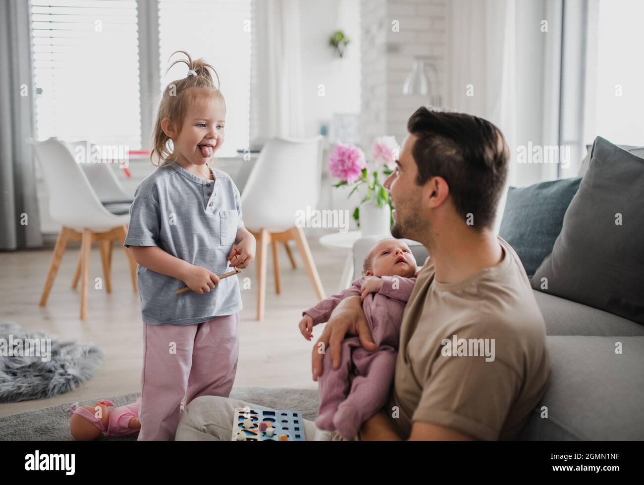 Jeune homme heureux prenant soin de son nouveau-né et petite fille à l'intérieur  à la maison, congé de paternité Photo Stock - Alamy
