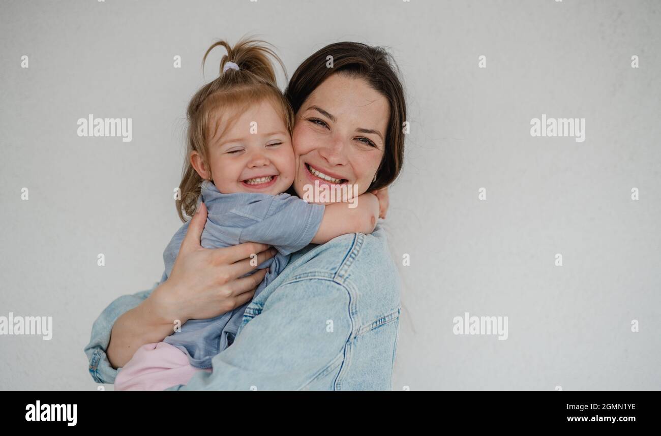 Portrait d'une jeune mère heureuse avec sa petite fille qui s'embrasse et regarde l'appareil photo, sur fond blanc. Banque D'Images