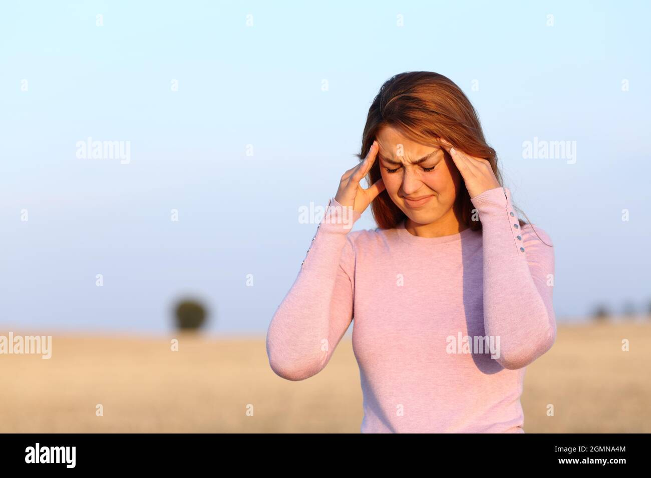 Une femme malade se plaint de maux de tête à l'extérieur dans le champ de récolte Banque D'Images