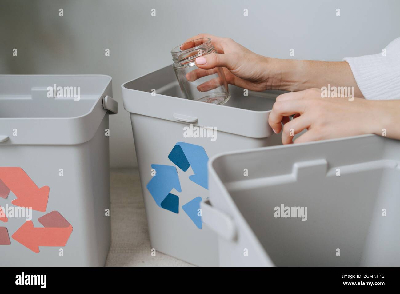 Les mains d'une femme triant les déchets encroquer les petits bacs de  recyclage à la maison. Ils ont des flèches de couleur différente. Tenir un  pot de verre Photo Stock - Alamy