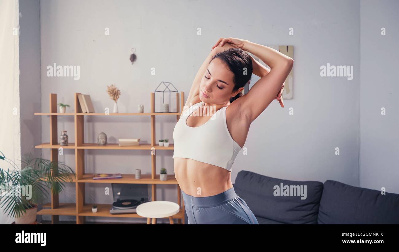 Jolie femme aux yeux fermés dans des vêtements de sport qui s'étirent à la  maison Photo Stock - Alamy