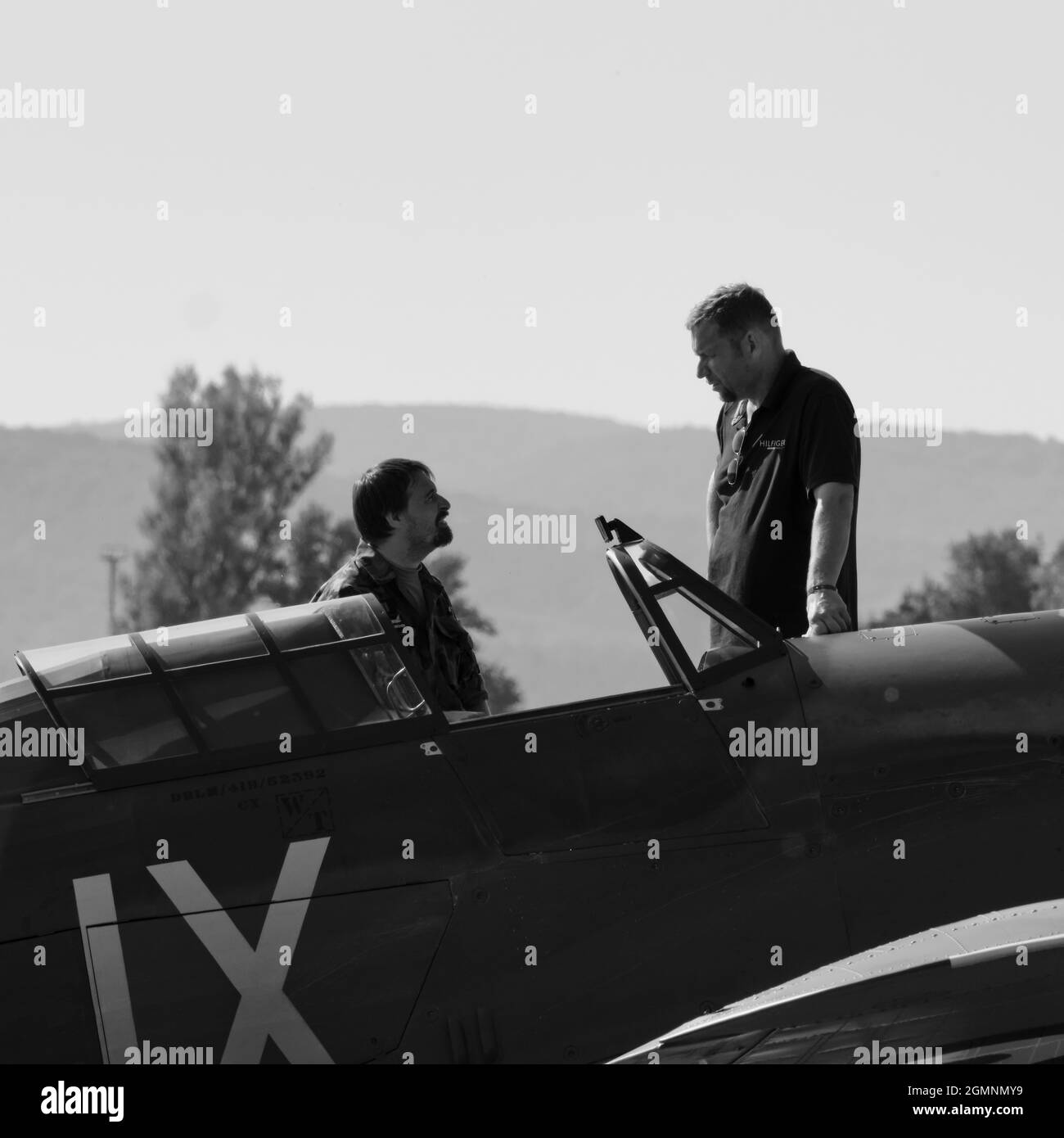 Grand et petit homme au-dessus du cockpit d'un avion historique en noir et blanc Banque D'Images