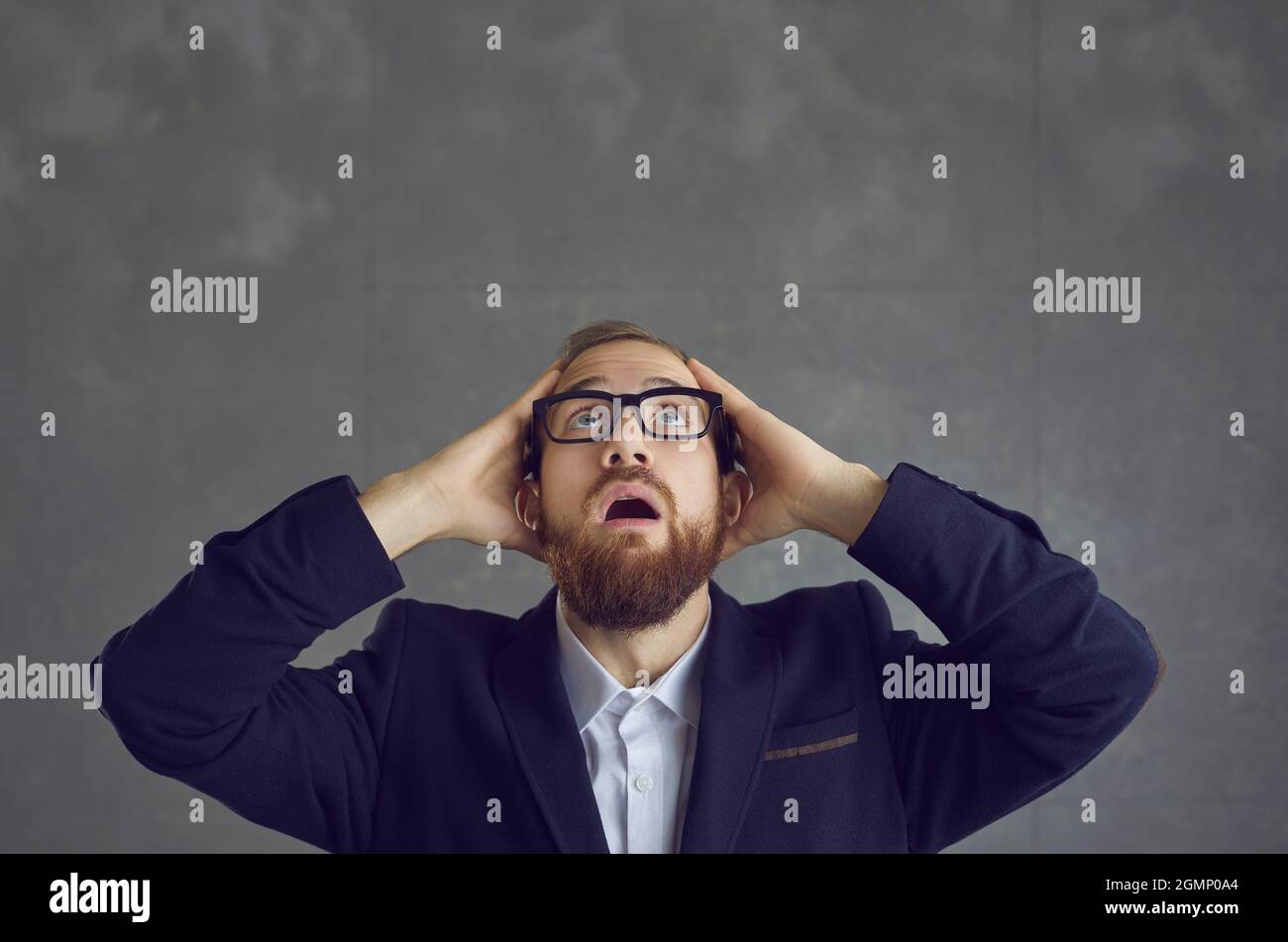 Homme d'affaires en costume et lunettes regardant avec l'expression de surprise, de choc et de peur Banque D'Images
