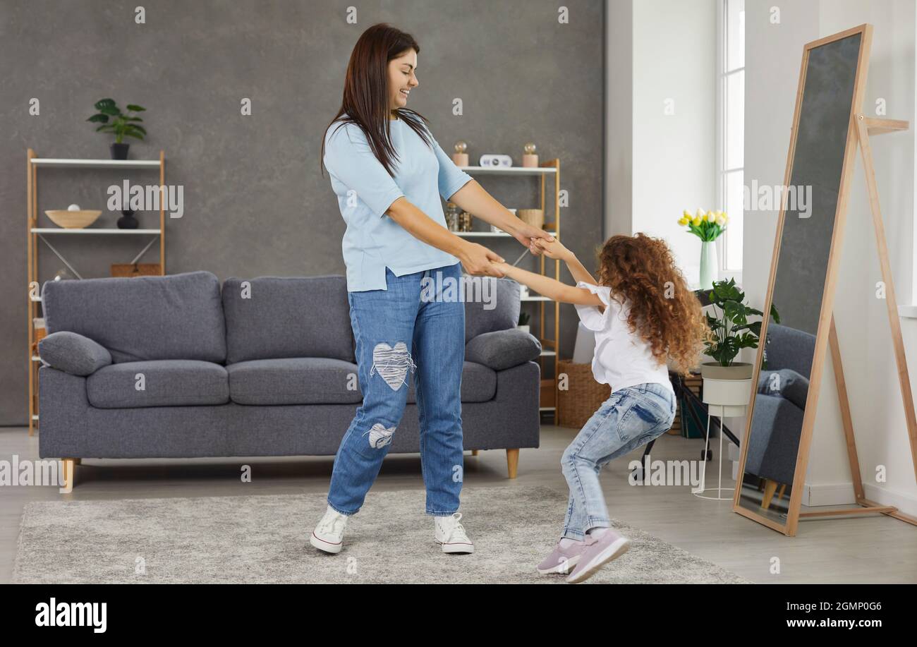 Bonne mère et petit enfant tenant les mains, dansant et s'amusant dans la salle de séjour Banque D'Images