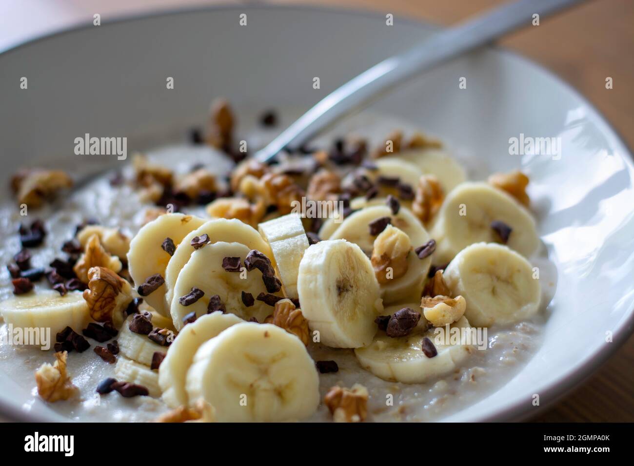 Porridge de flocons d'avoine sain avec banane, noix et pointes de cacao. Banque D'Images