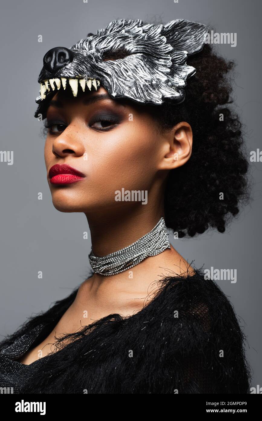 confiante afro-américaine femme en loup halloween masque et collier en  métal regardant la caméra isolée sur gris Photo Stock - Alamy
