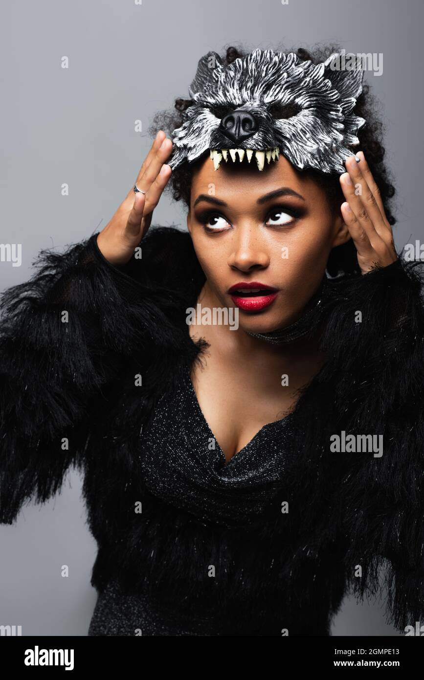 jolie femme africaine américaine ajustement loup halloween masque isolé sur gris Banque D'Images