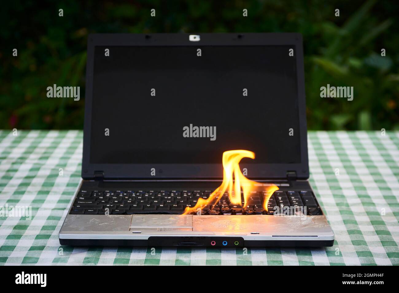 Ordinateur portable brûlant dans des flammes sur un bureau, risque d'incendie. Perte de données précieuses.Défaillance de la batterie défectueuse.Accident informatique.Ordinateur portable explose Banque D'Images