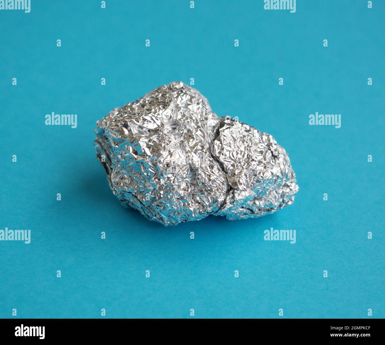 Aluminium. Feuille d'aluminium argentée avec des feuilles de papier d'aluminium froissés et brillants sur fond bleu. Les prix de l'aluminium ont atteint un record. Banque D'Images