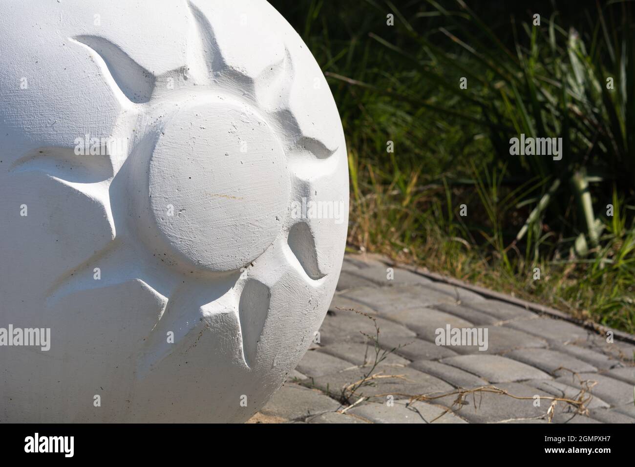 Boule décorative en ciment avec motif soleil. Élément de banc de rue. Banque D'Images