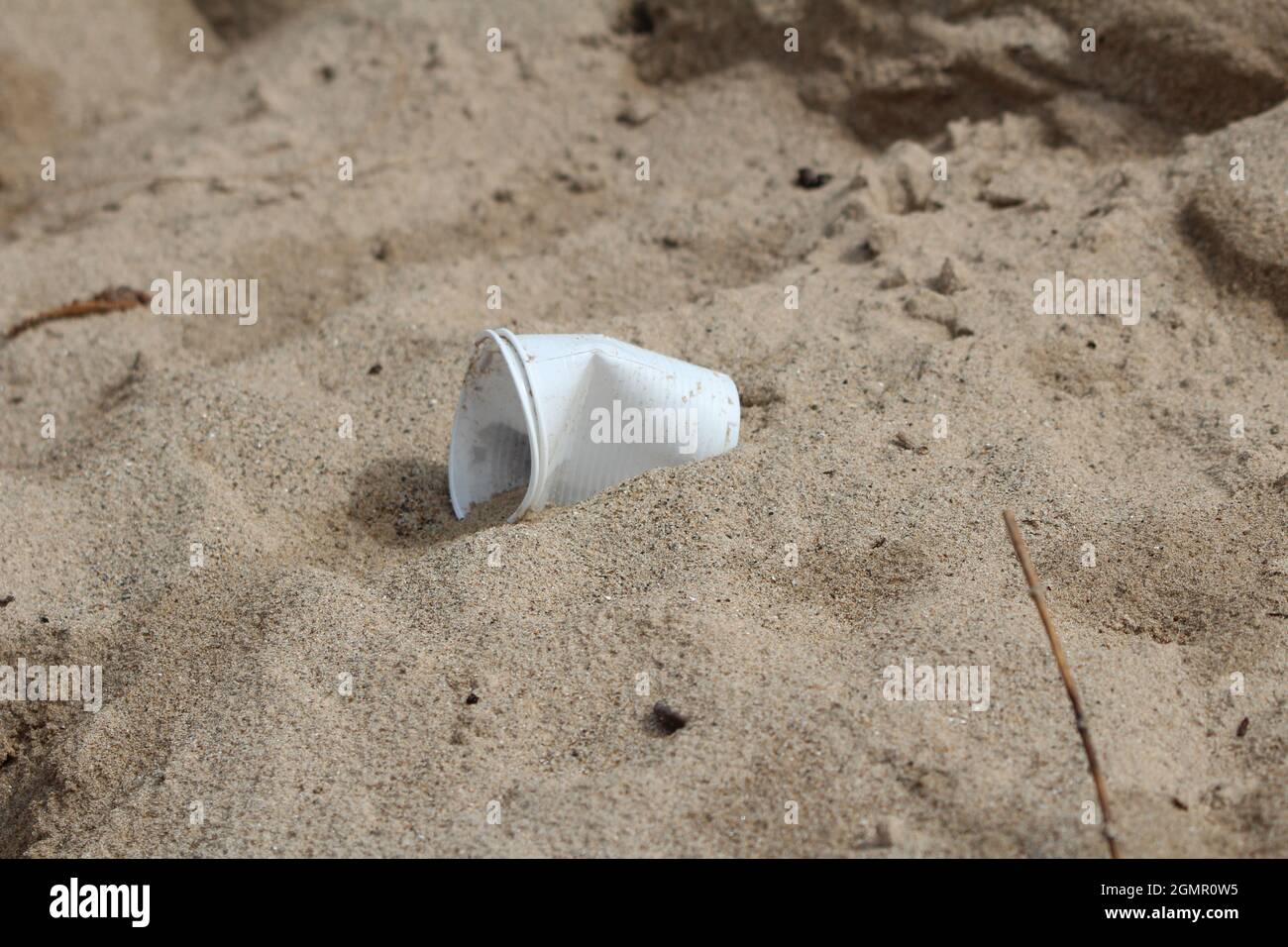 Une tasse en plastique laissée dans le sable à Newborough Forest, au pays de Galles. Banque D'Images