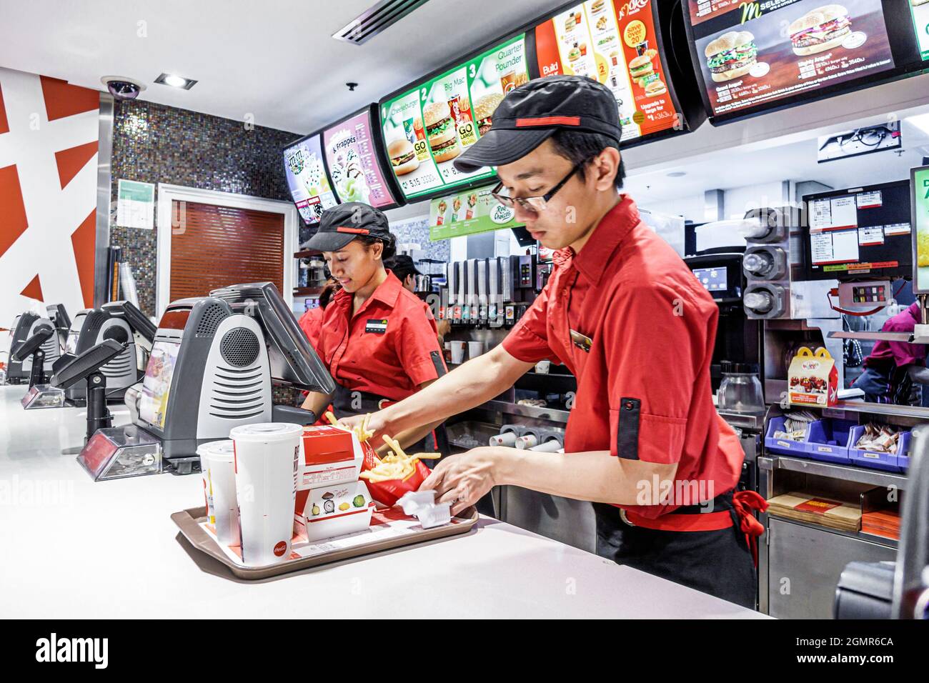 Sydney Australie, Circular Quay, McDonald's restaurant fast food counter homme asiatique homme, employés travaillant à la préparation de l'uniforme de commande femme noire Banque D'Images