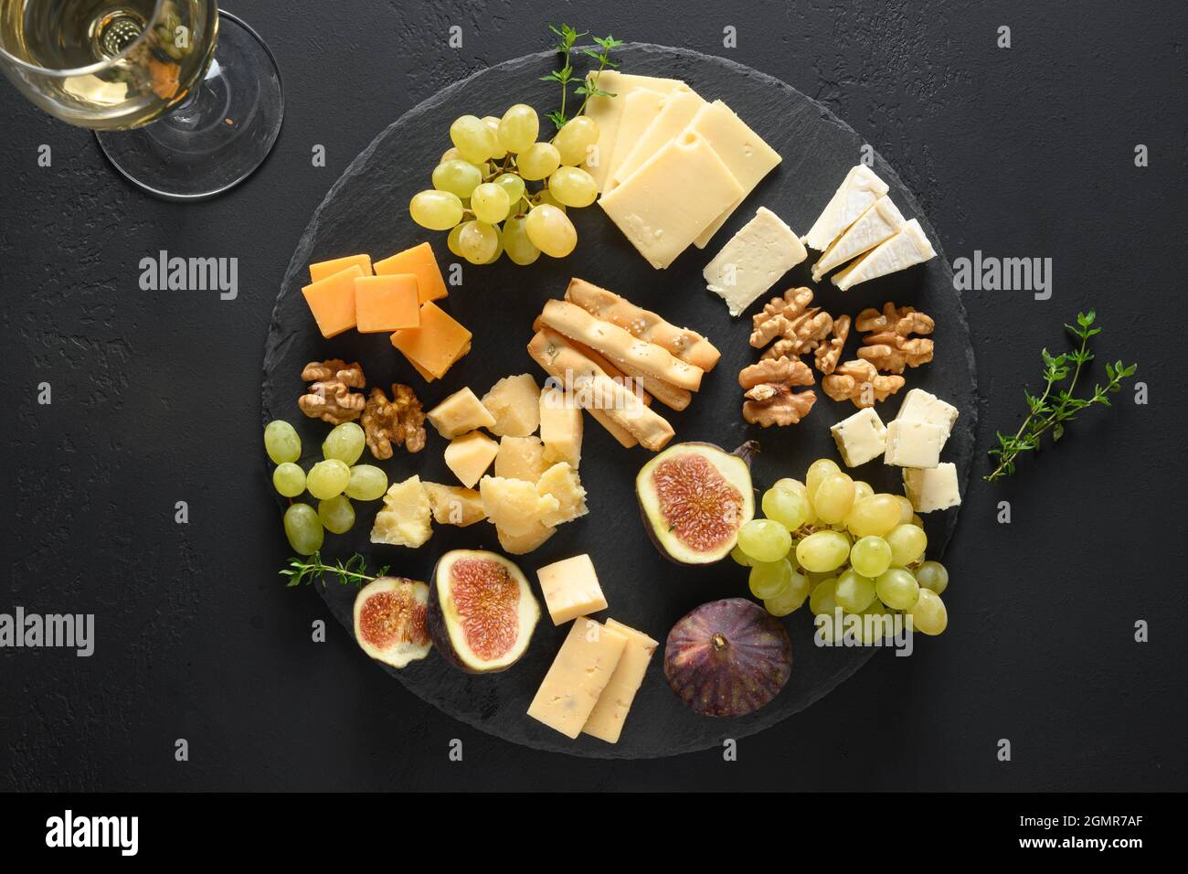 Plateau de fromages avec raisins, noix, figues sur fond d'ardoise noire. Vue de dessus. En-cas gastronomique festif. Banque D'Images