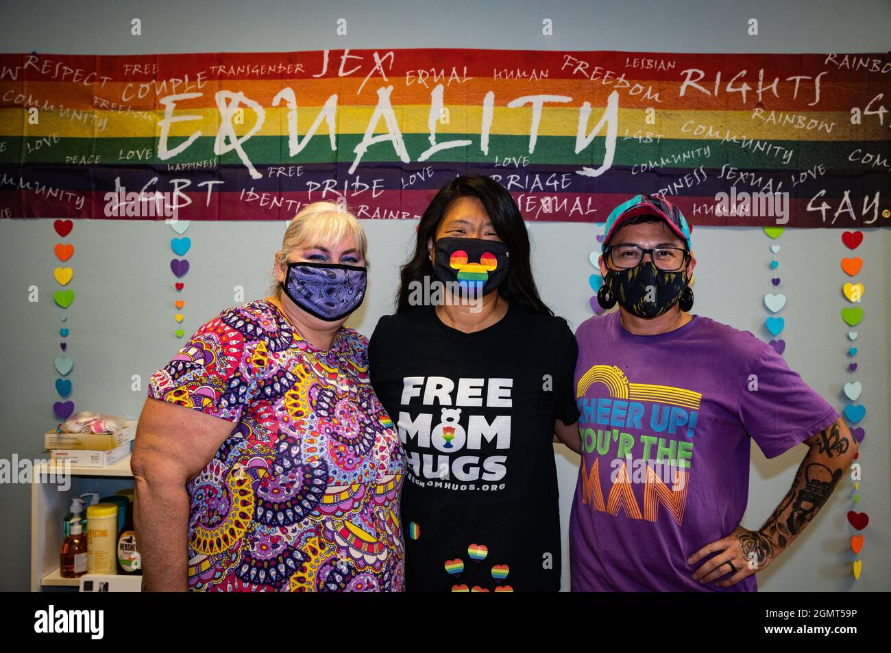 Photo de l'équipe de direction du Merced Pride Centre Cristina Vara (lft), Jennifer McQueen (cntr) et Eli Sachse (rt) sous un signe d'égalité arc-en-ciel. Banque D'Images