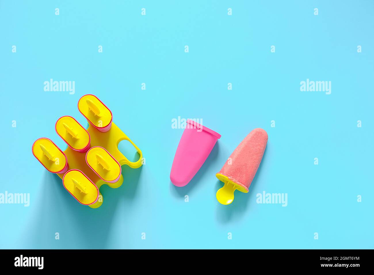 Pop-sicles faits maison. Crème glacée à la fraise naturelle dans des moules en plastique brillant sur fond bleu avec espace de copie. Vue de dessus modèle de Flat Lay pour votre. Banque D'Images