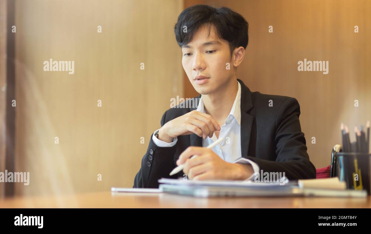 Jeune homme d'affaires asiatique de confiance travaillant à son bureau dans un bureau moderne Banque D'Images