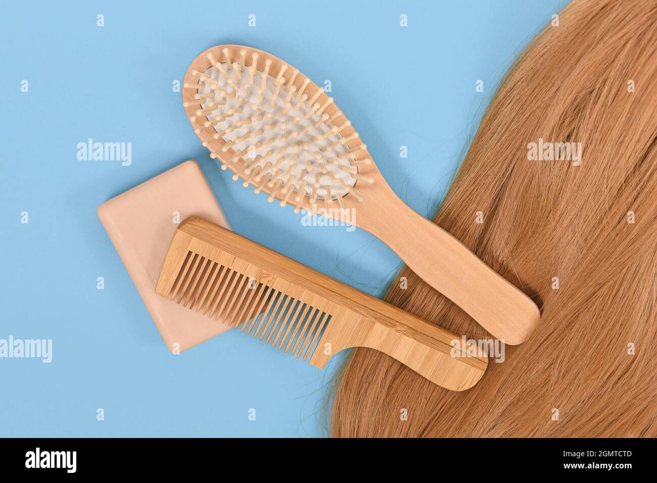 Soin santé des cheveux avec barre de shampooing écologique solide, peigne en bois et brosse sur fond bleu Banque D'Images