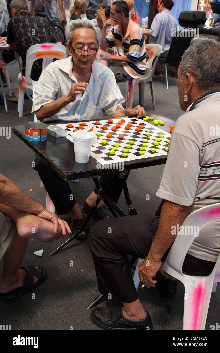 Chinatown, Singapour - 1er avril 2011 l'homme fumeur s'est concentré sur son jeu de dames dans cette place ouverte et bruyante du centre de Chinatown à Singapour Banque D'Images