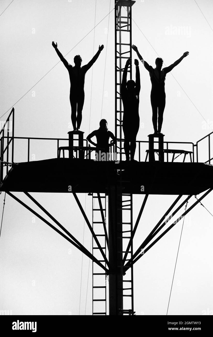 Hong Kong, 1983; quatre plongeurs ont silhoueté au sommet d'un haut-plan de plongée. Fait partie du spectacle quotidien de l'Ocean Park, un parc à thème sur le côté sud de Banque D'Images