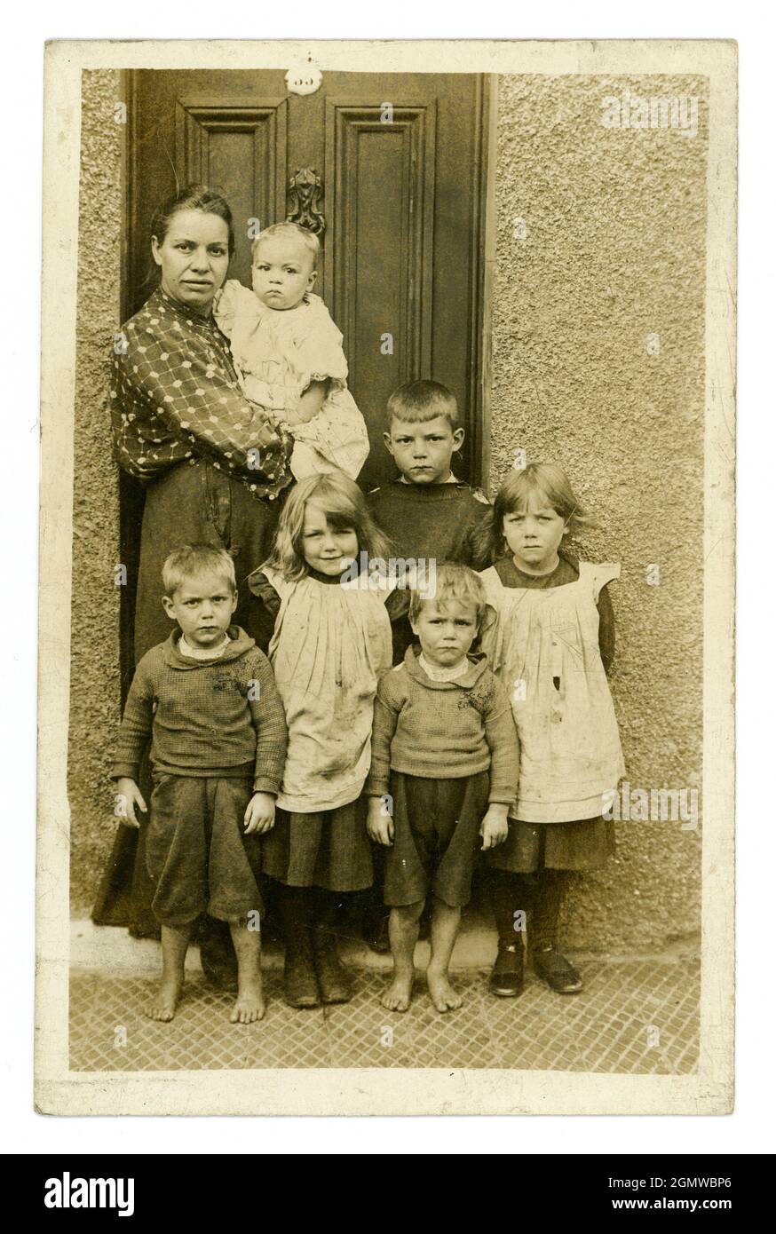 Original, très clair, l'époque édouardienne portrait carte postale de mère typique de classe ouvrière pauvre avec une grande famille de six jeunes enfants sérieux et un bébé dans ses bras, certains enfants sont pieds nus, portant des vêtements sales et déchirés. Les filles sont vêtues de pinafores, les garçons portant des pull-overs, à deux pas, du studio de J.H. Ormerod, Seacombe, Wallasey, The Wirral, Angleterre, Royaume-Uni vers 1907 Banque D'Images