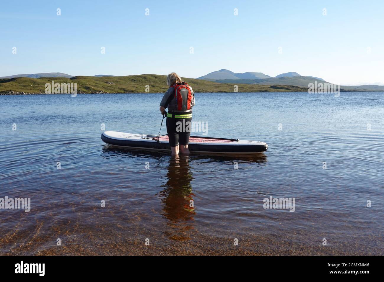 Une dame plus âgée qui utilise des planches à rapaddle sur le Loch Laidon, dans les Highlands écossais Banque D'Images