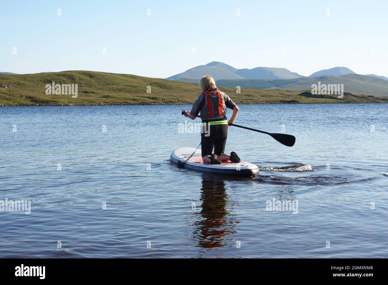 Une dame plus âgée qui utilise des planches à rapaddle sur le Loch Laidon, dans les Highlands écossais Banque D'Images