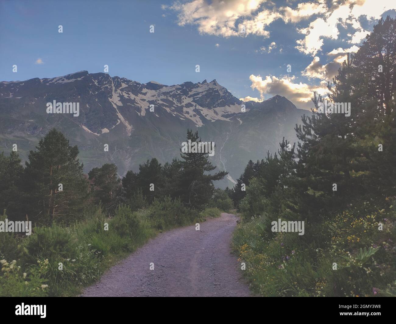 Une route de terre dans les montagnes. Magnifique paysage des montagnes du Caucase au coucher du soleil. Route de randonnée vide. Banque D'Images