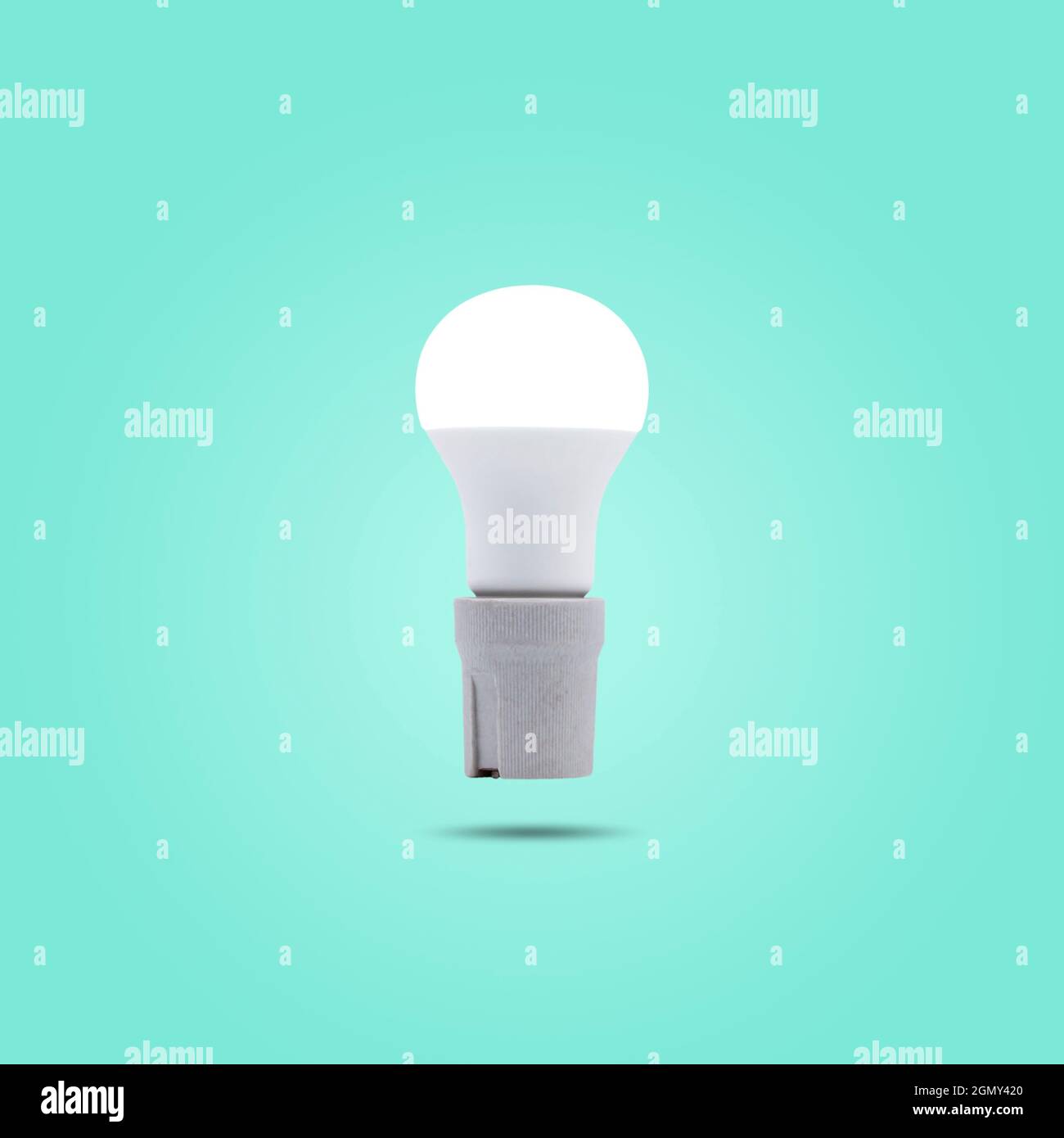 Lampe LED à économie d'énergie 230 v dans une prise en céramique isolée sur fond vert pastel. Banque D'Images Lampe LED à économie d'énergie 230 v dans une prise en céramique isolée sur fond vert pastel. Banque D'Images