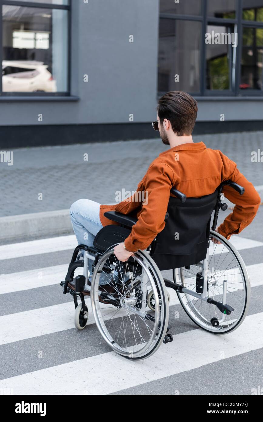 homme handicapé se déplaçant sur un passage en fauteuil roulant Banque D'Images