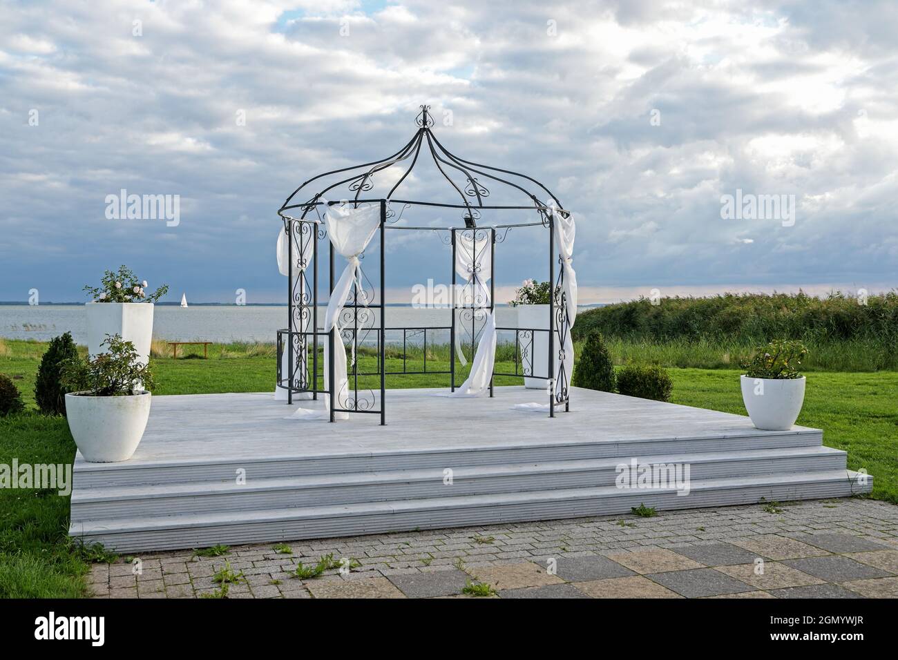 Pavillon de fer décoré de tissus blancs pour une cérémonie de mariage sur une plate-forme sur le bord du lac sous un ciel nuageux, espace de copie, foyer sélectionné Banque D'Images