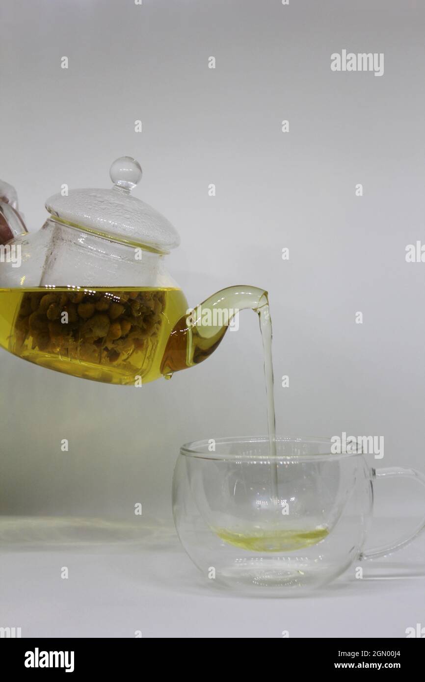 Verser le thé aux feuilles d'or dans une tasse de thé transparente Banque D'Images