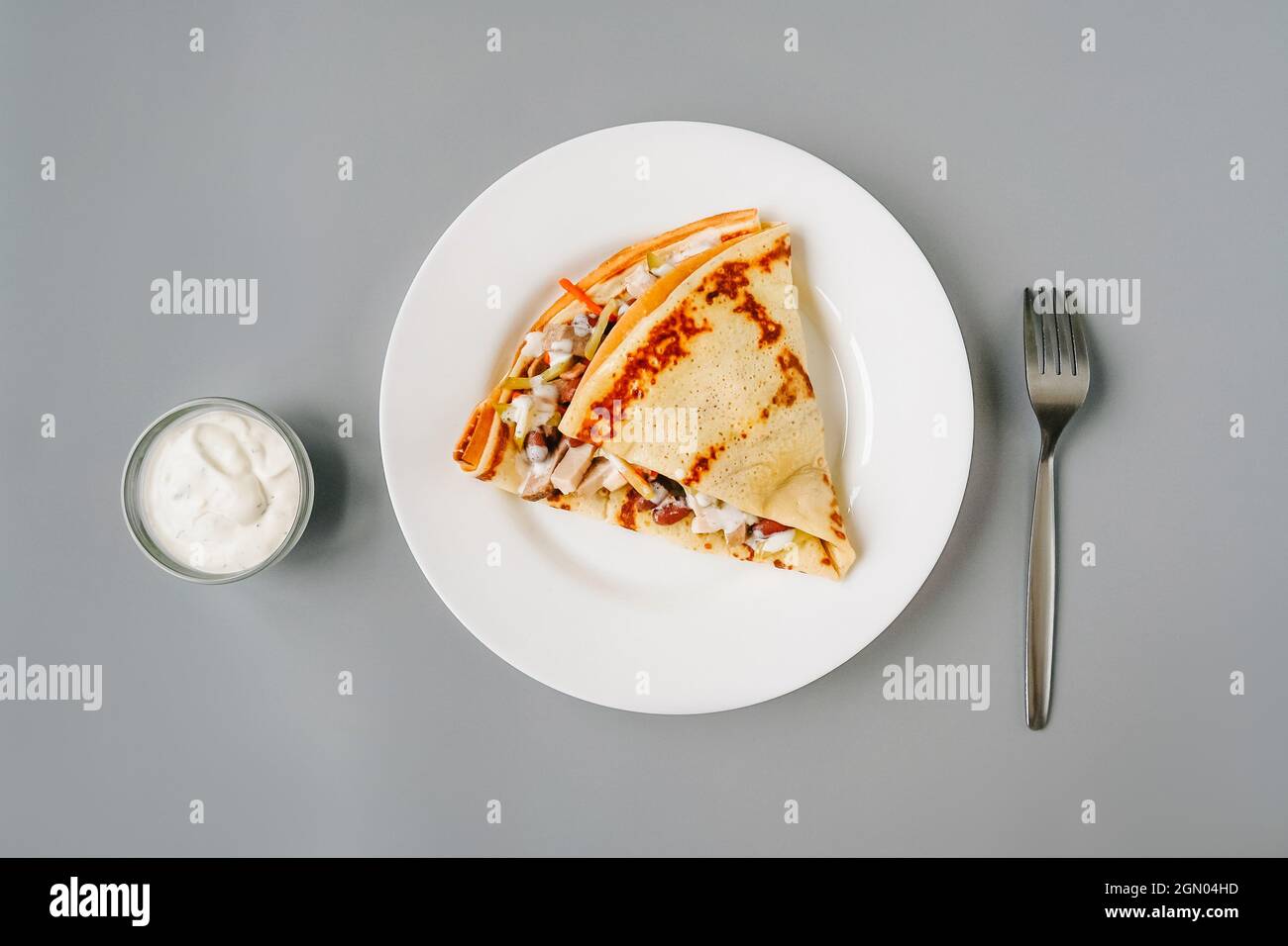 Personne mangeant des crêpes avec garniture. Petit déjeuner savoureux sur fond gris. Fourchette et sauce. Banque D'Images