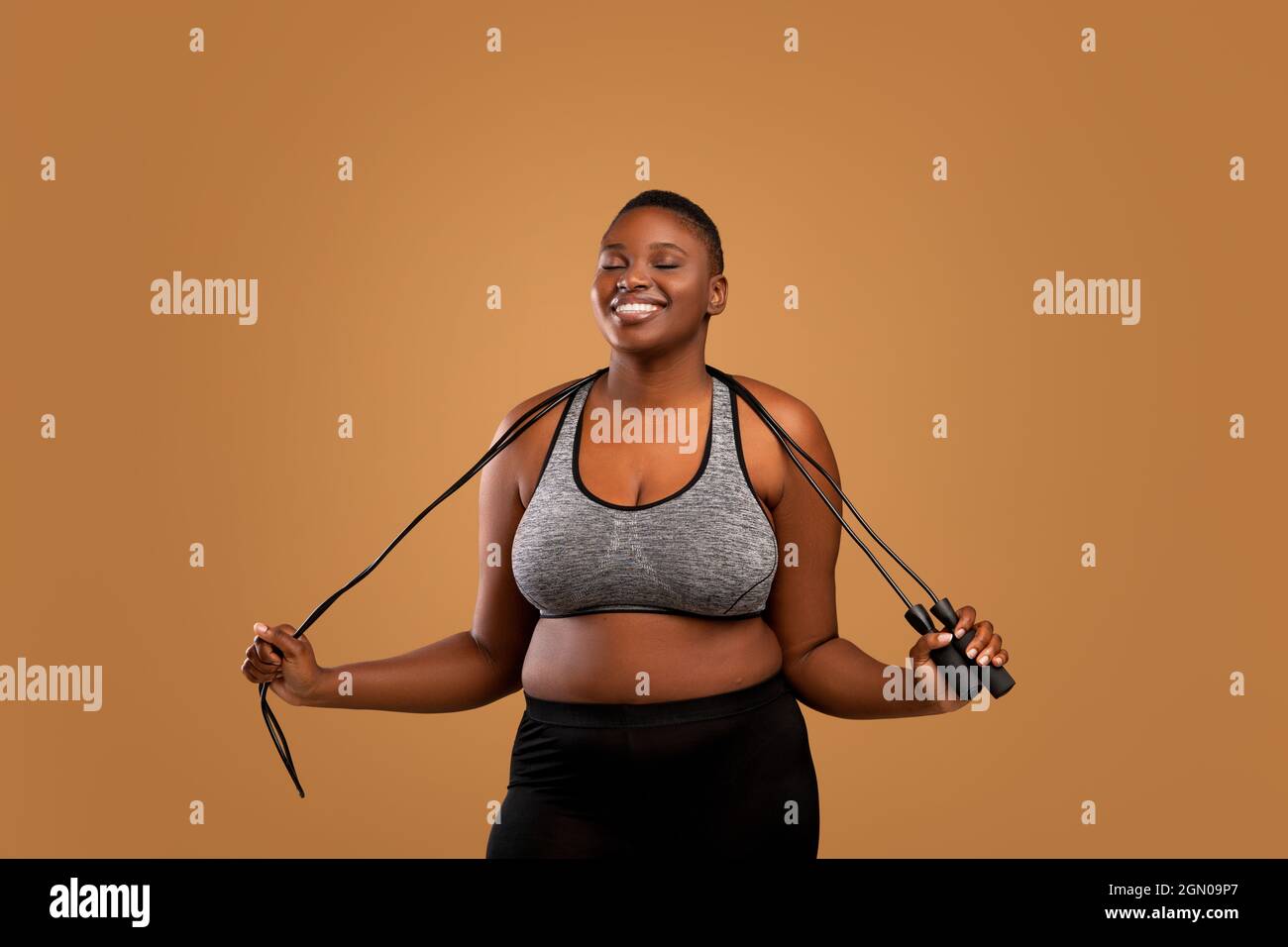 Black Chubby femme posant avec corde de saut au Studio Banque D'Images