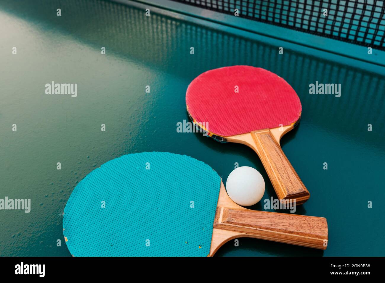 Raquettes de tennis de table et balles de ping-pong sur une surface de table verte avec filet, mise au point sélective Banque D'Images
