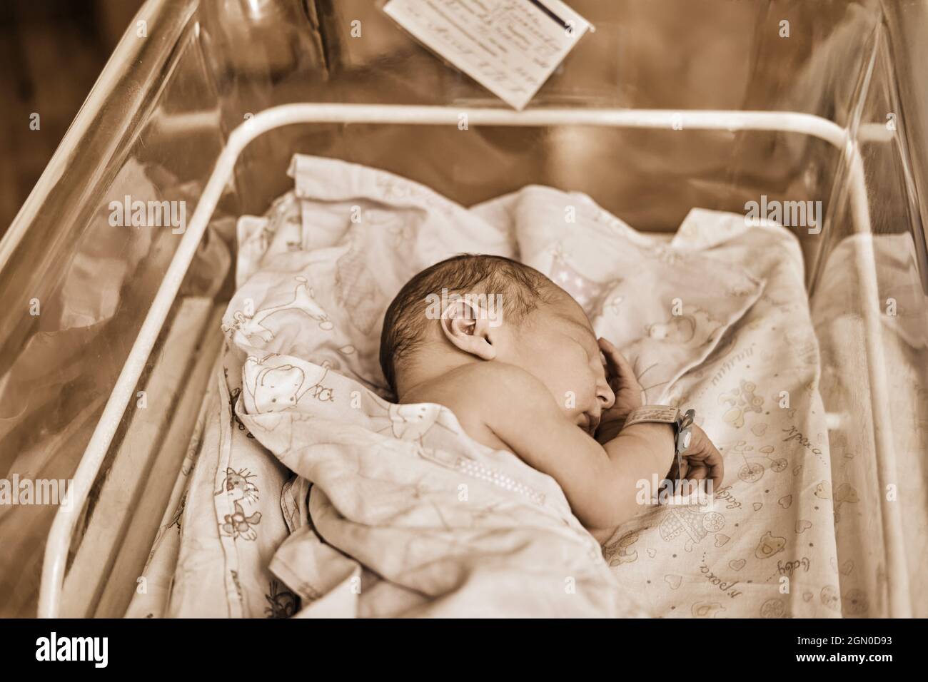 Un nouveau-né avec un bracelet de maternité sur son bras dort dans un  berceau. Un enfant nouvellement né dans un lit de clinique derrière un  verre transparent Photo Stock - Alamy