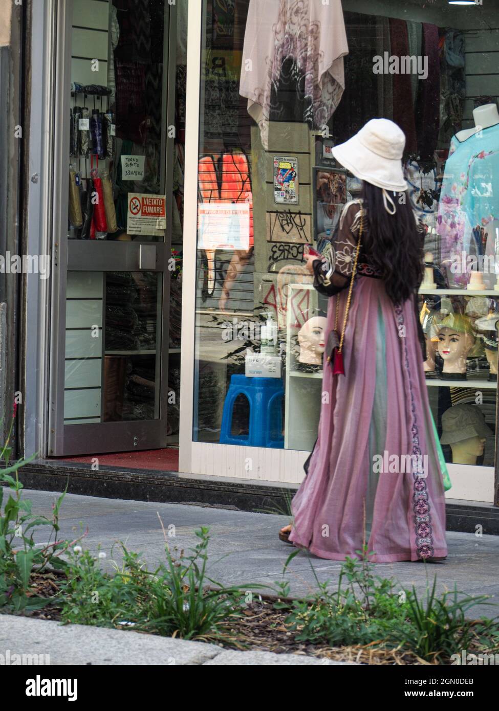 MILAN, ITALIE - 08 août 2021 : gros plan d'une femme marchant sur un trottoir avec une longue robe violette, Milan, Italie Banque D'Images