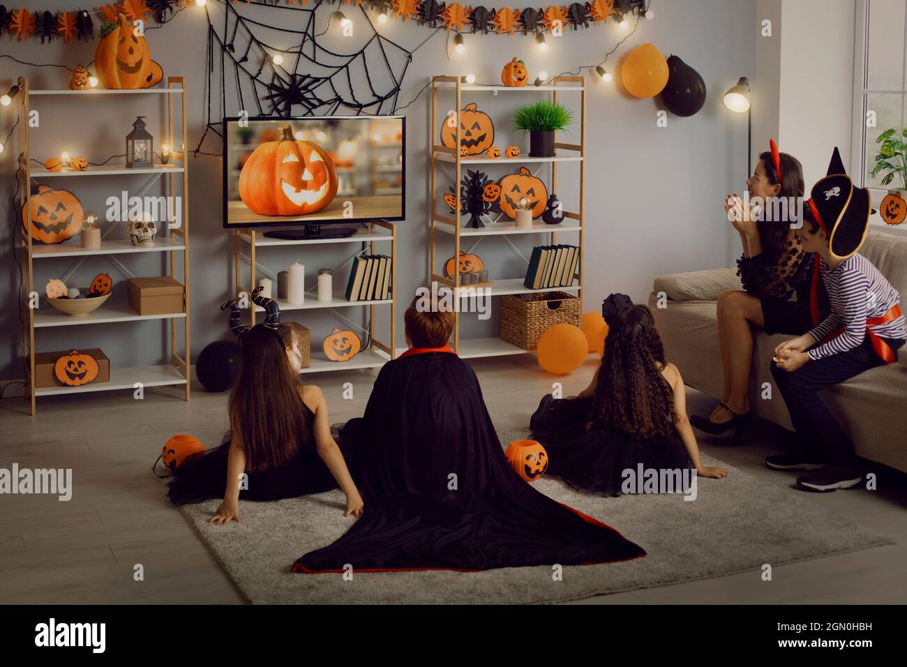 Les enfants en costumes effrayants regardent un film effrayant lors d'une fête d'Halloween à la maison Banque D'Images