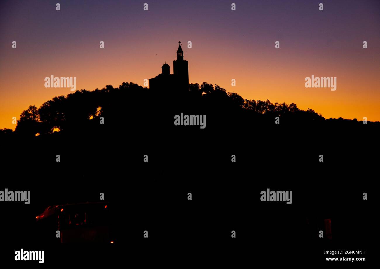 La silhouette noire d'une ancienne tour sur une montagne sur fond de coucher de soleil. Banque D'Images