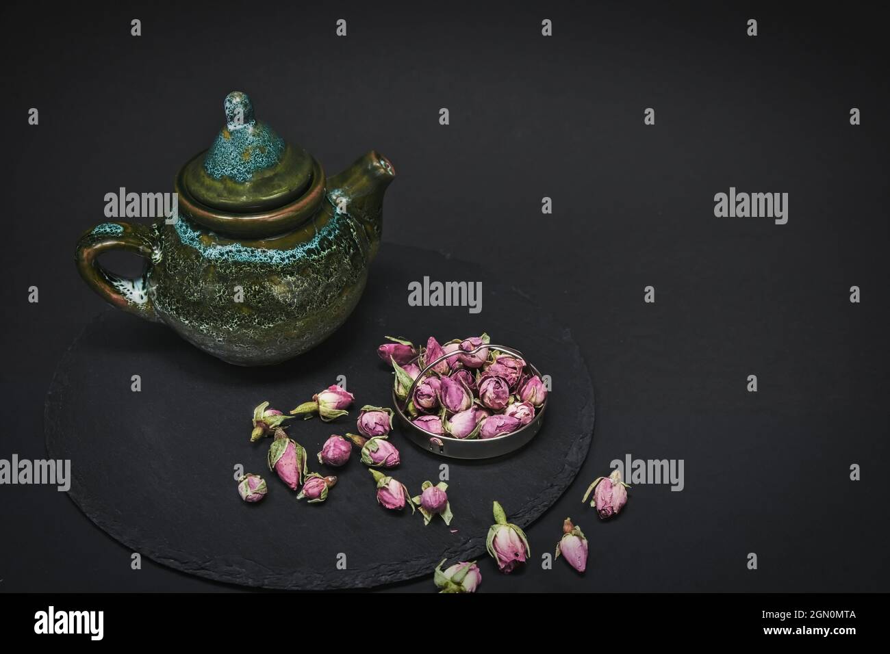 Boutons de rose de thé séché et théière en céramique vintage pour cérémonie du thé dans le style chinois sur fond noir. Banque D'Images