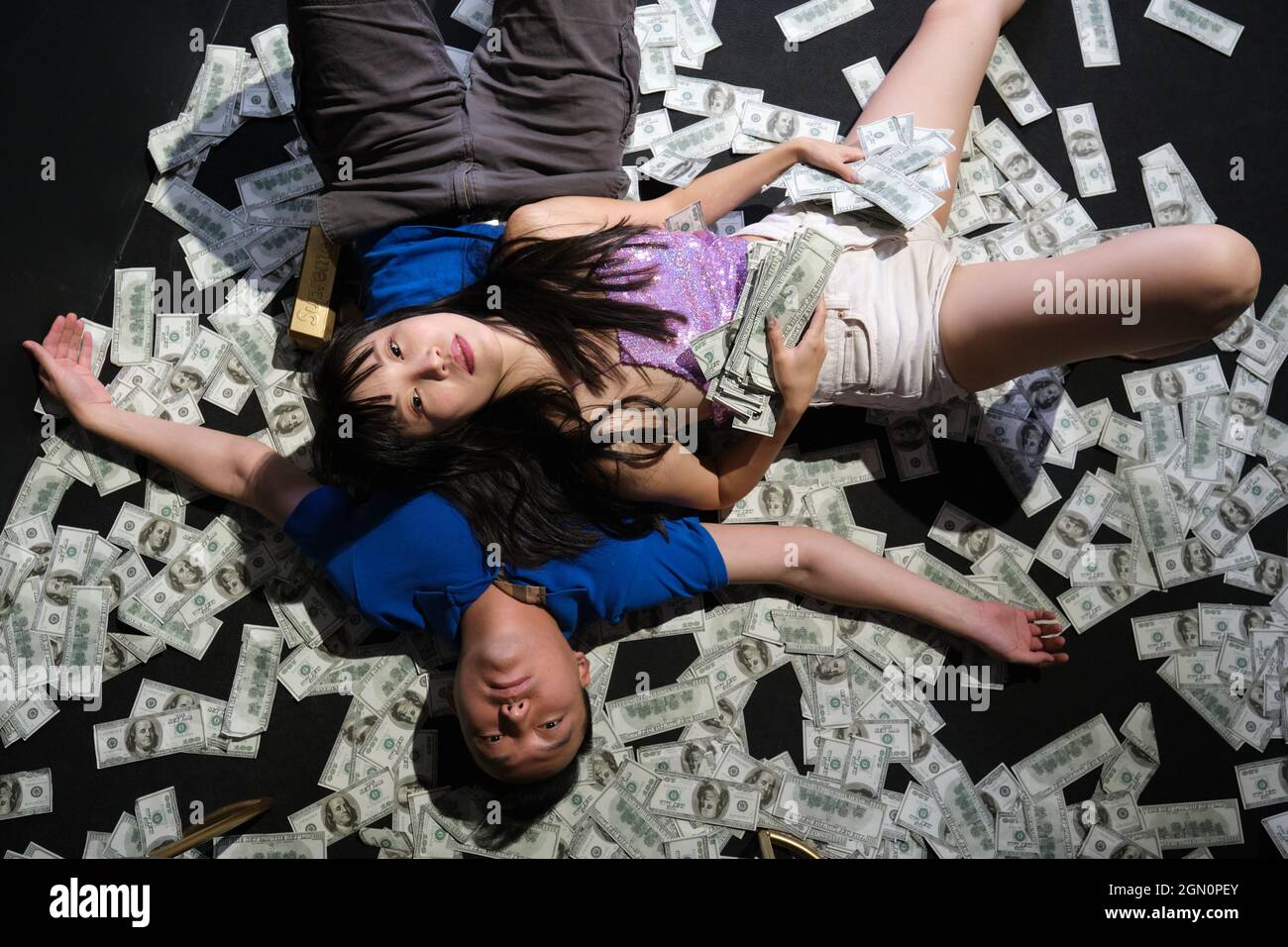 Mort d'un jeune couple asiatique entouré de billets de dollars. Suicide par balle. Banque D'Images